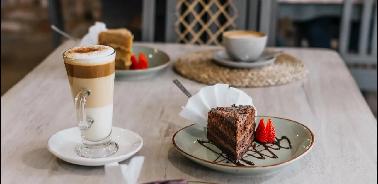 Latte with chocolate cake slice on side plate