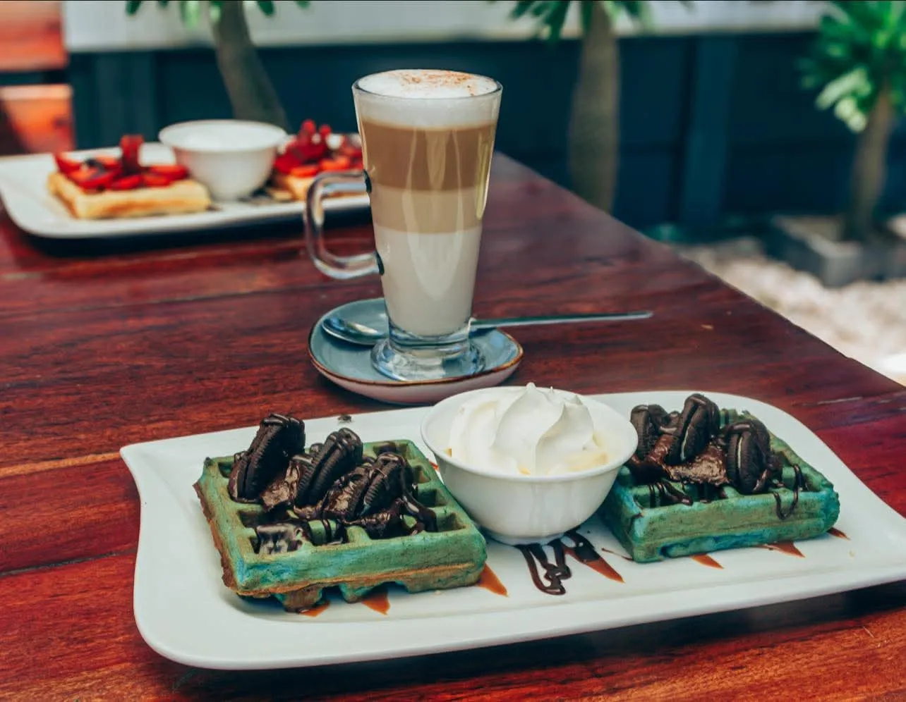 Latte next to waffles with oreos on top